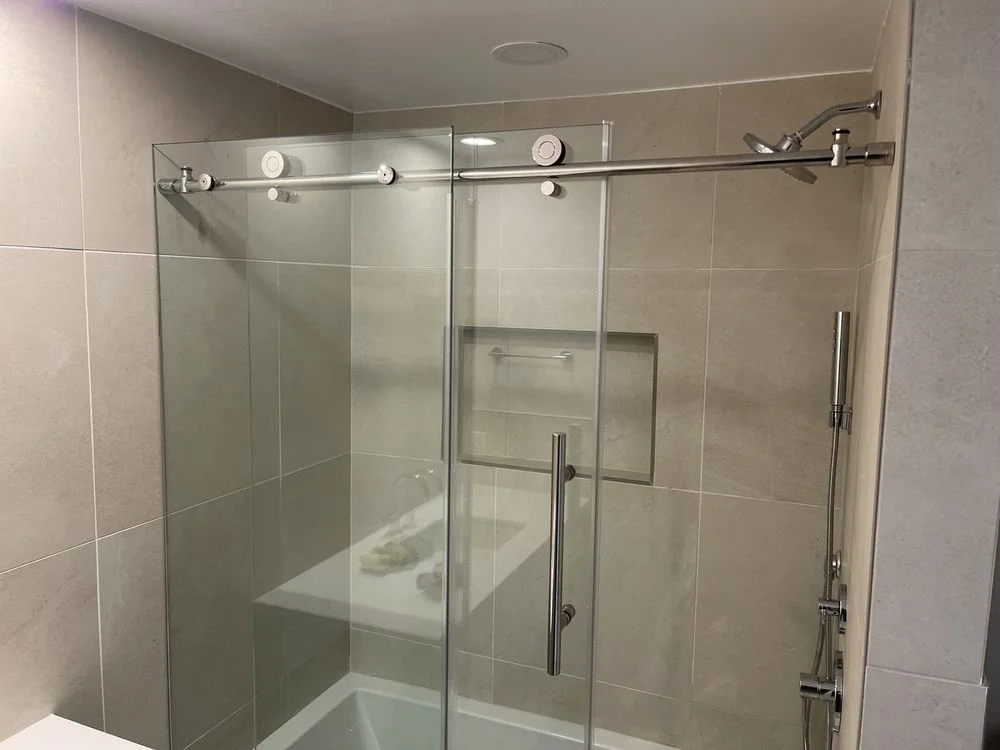 A finished bathroom renovation in an Encinitas home showing a walk-in shower with large-format tile, a wall-mounted vanity, and updated lighting. The space reflects a clean, coastal-appropriate design built to handle the local humidity and salt air.