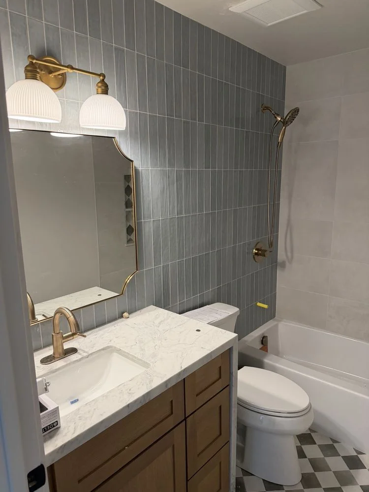 A remodeled bathroom in an Encinitas home showing a newly installed wall-mounted vanity with an undermount sink, updated faucet hardware, and a lit mirror above. Coastal-appropriate finishes and clean lines reflect the style common in North County San Diego bathroom upgrades.
